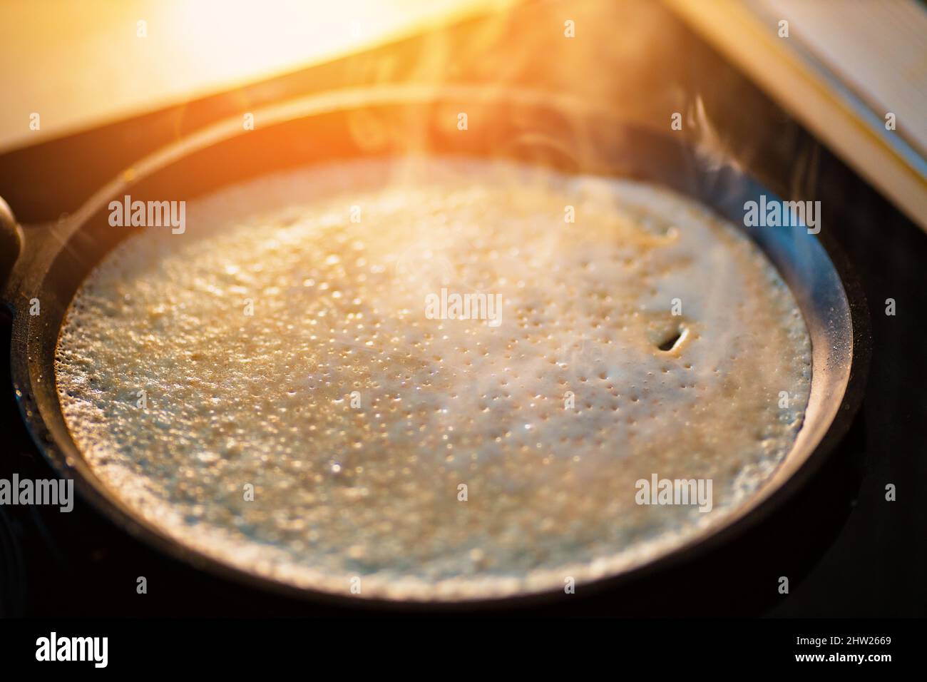 Pancake is baked in black cast iron skillet and there is smoke