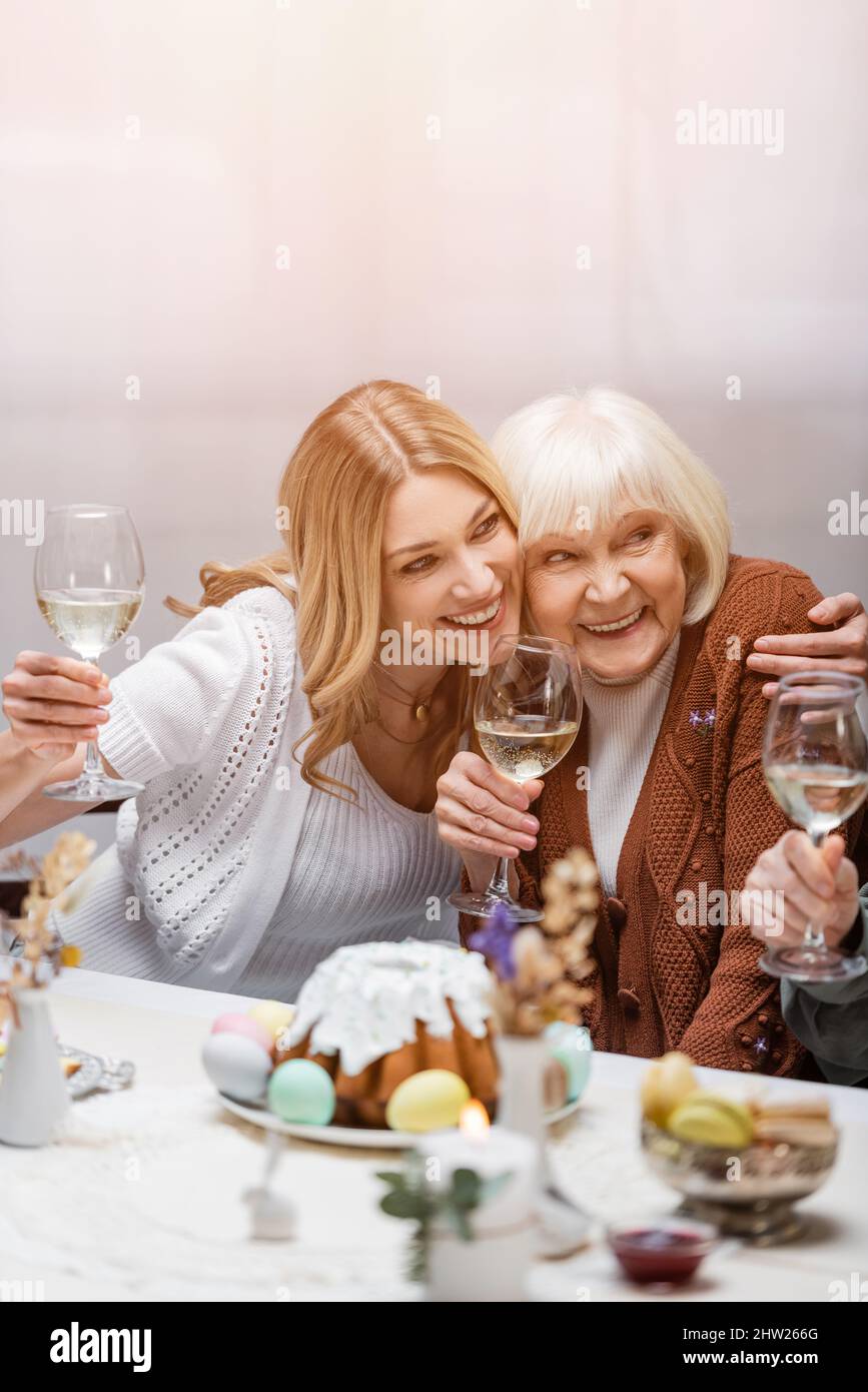 happy mother and daughter with wine glasses embracing during easter dinner,stock image Stock Photo