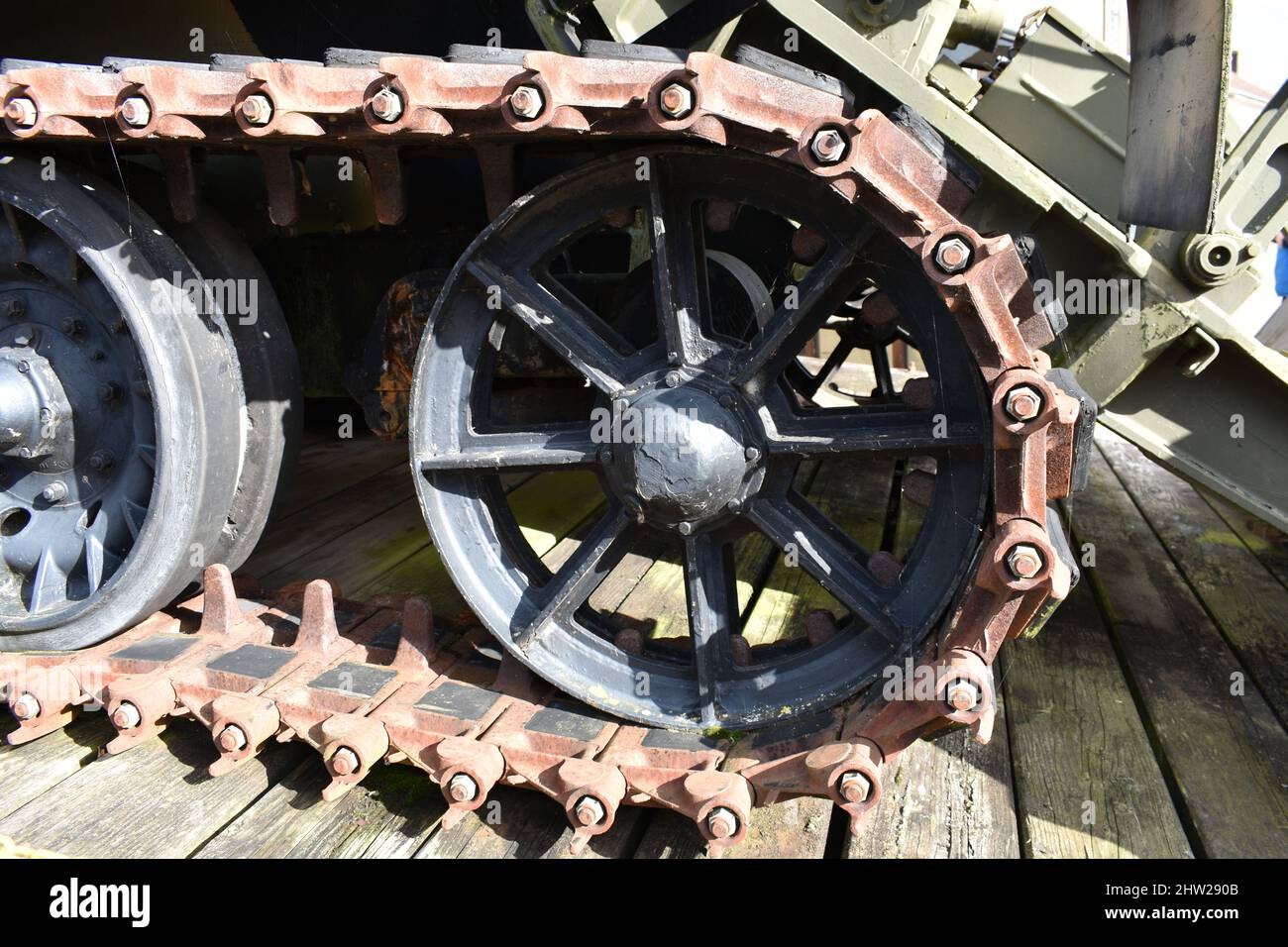 close up of old military tank wheel on caterpillar tracks. A vintage army vehicle wheel outside a museum on a wooden plank floor Stock Photo