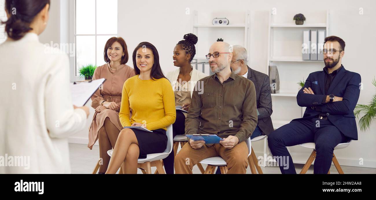 Satisfied entrepreneurs listen to presentation by female coach in corporate business. Stock Photo