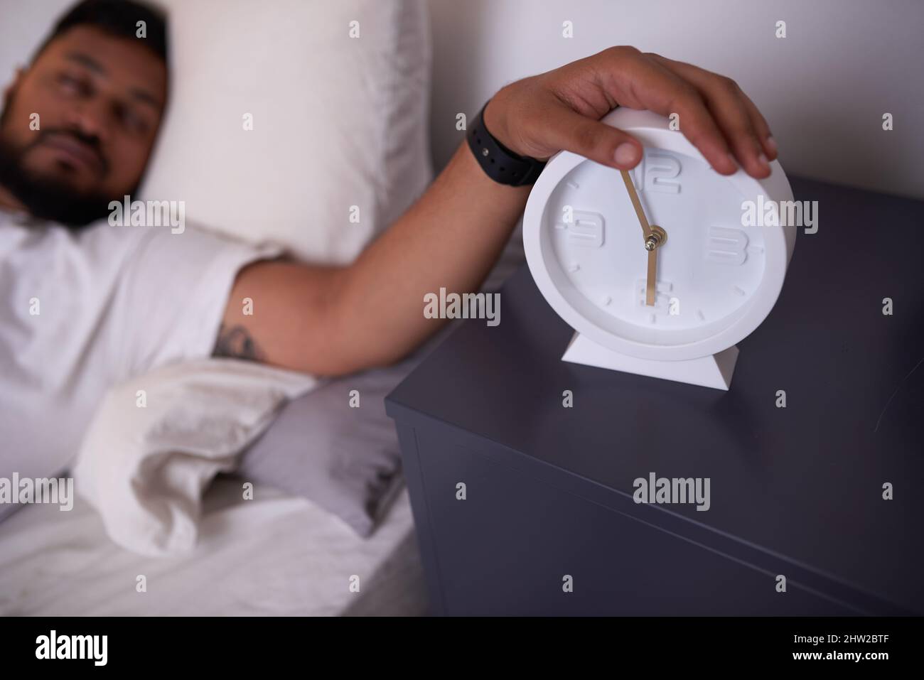 A man turns off his alarm at 6 am while he carries on sleeping Stock