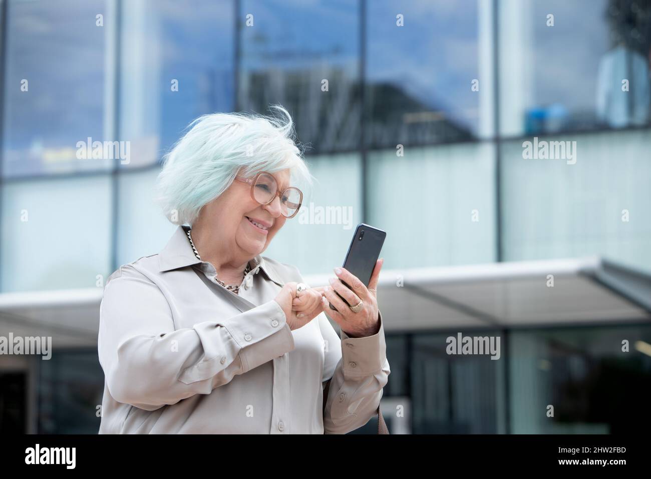 older business woman typing on her cell phone outdoors Stock Photo
