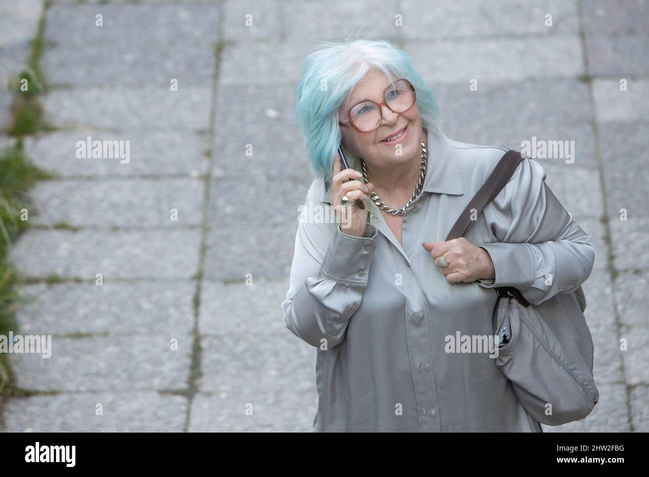fashion older woman talking on cell phone outdoors as seen from above with copy space Stock Photo