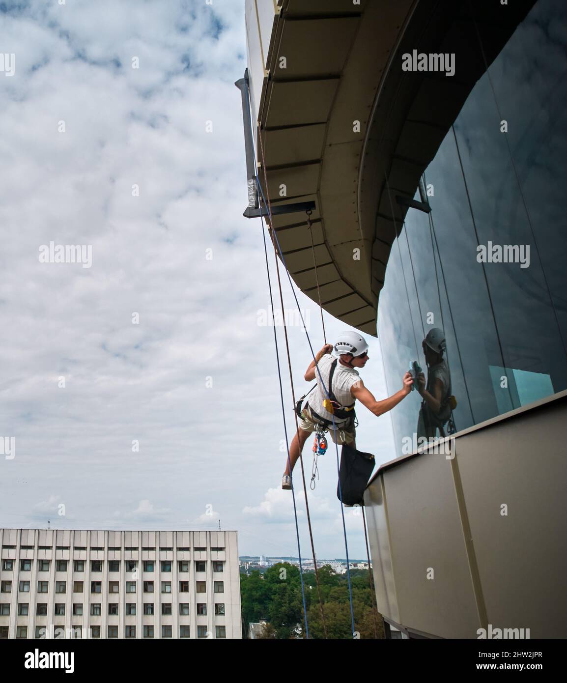 Industrial mountaineering worker hanging on climbing rope and cleaning