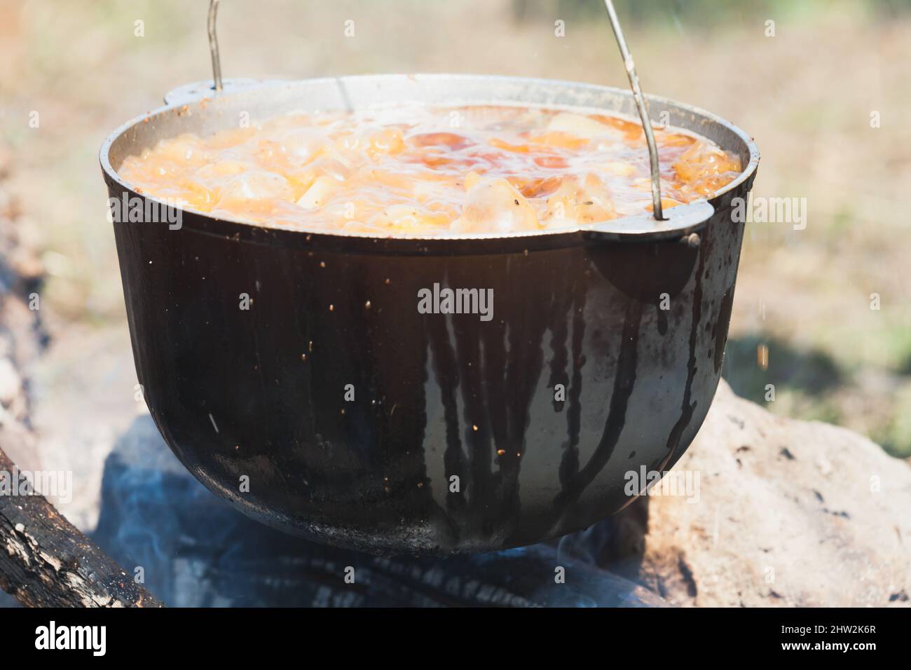 Cauldron with boiling soup is on open fire outdoor camping meal