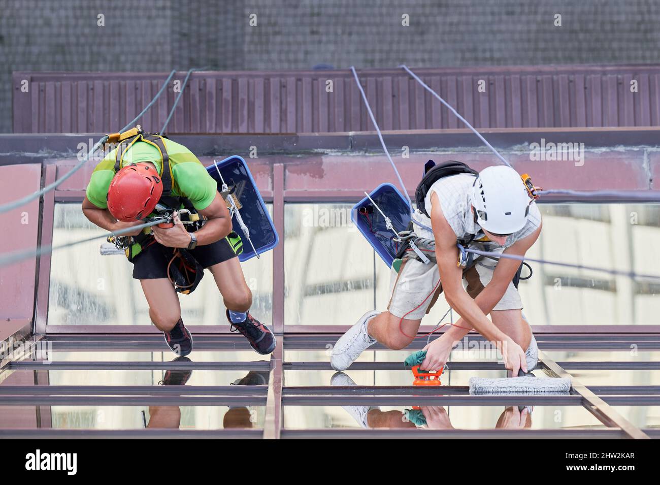 Industrial mountaineering workers washing glass windows of highrise