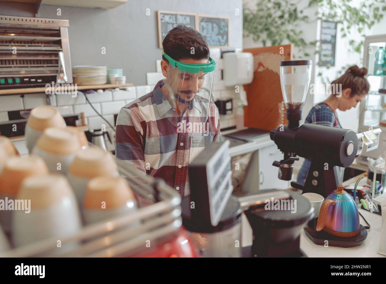 Smiling barista with mustache in protective visor preparing coffee Stock Photo