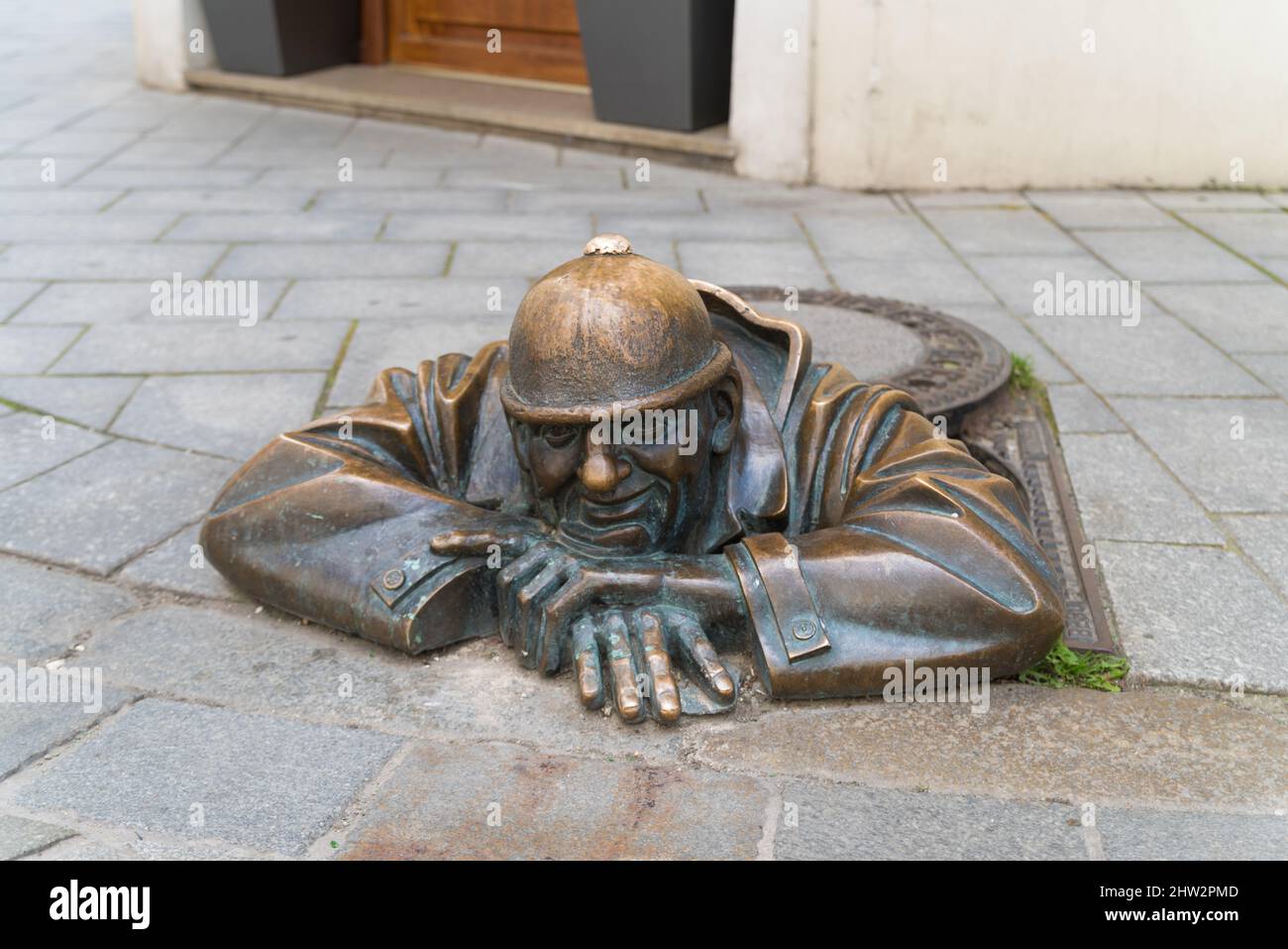 BRATISLAVA, SLOVAKIA - JULY 27, 2020: The bronze statue, with a grin on his face, peeks his head from underneath a manhole cover in the Old Town and h Stock Photo