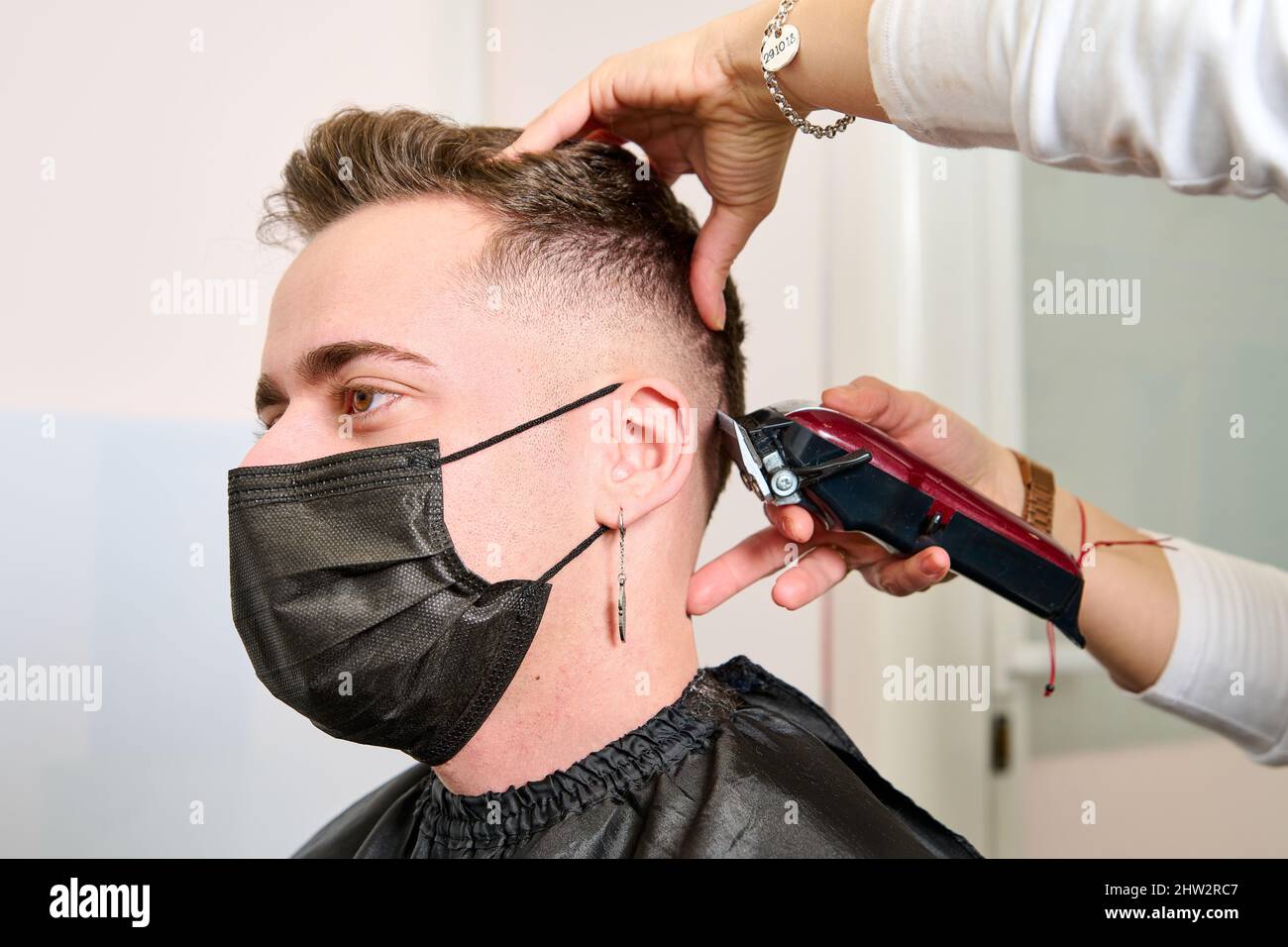a man sitting in the barbershop while the hairdresser was styling his hair with an electric clipper Stock Photo