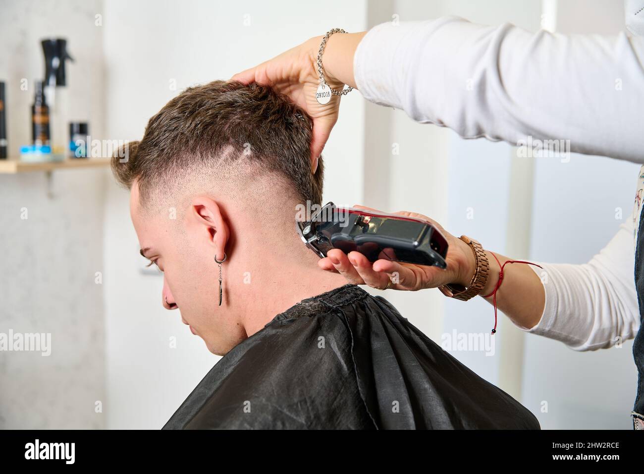 a man sitting in the barbershop while the hairdresser was styling his hair with an electric clipper Stock Photo