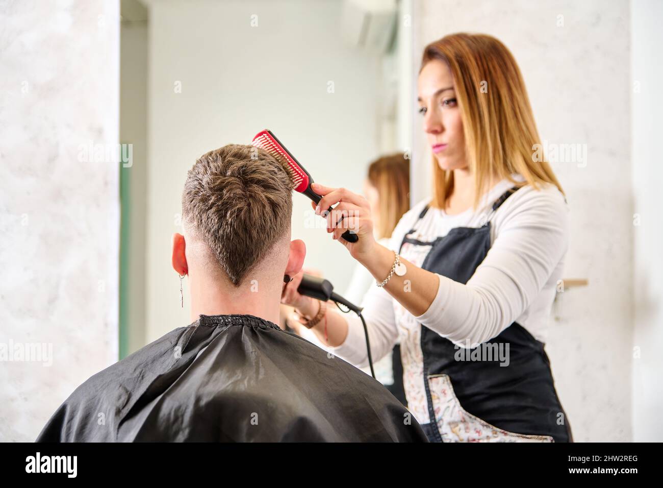 Hairdresser cutting hair and styling a client in the barbershop Stock Photo