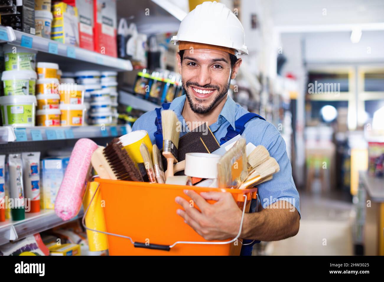 Workman holding basket with picked tools in paint store Stock Photo