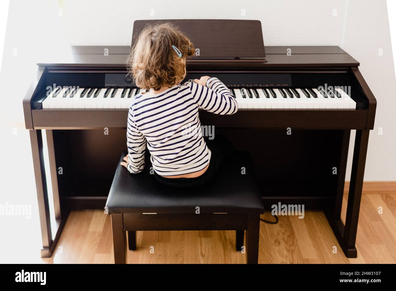 Pretty 3 year old girl practices playing the piano, seen from behind, copy  space Stock Photo - Alamy