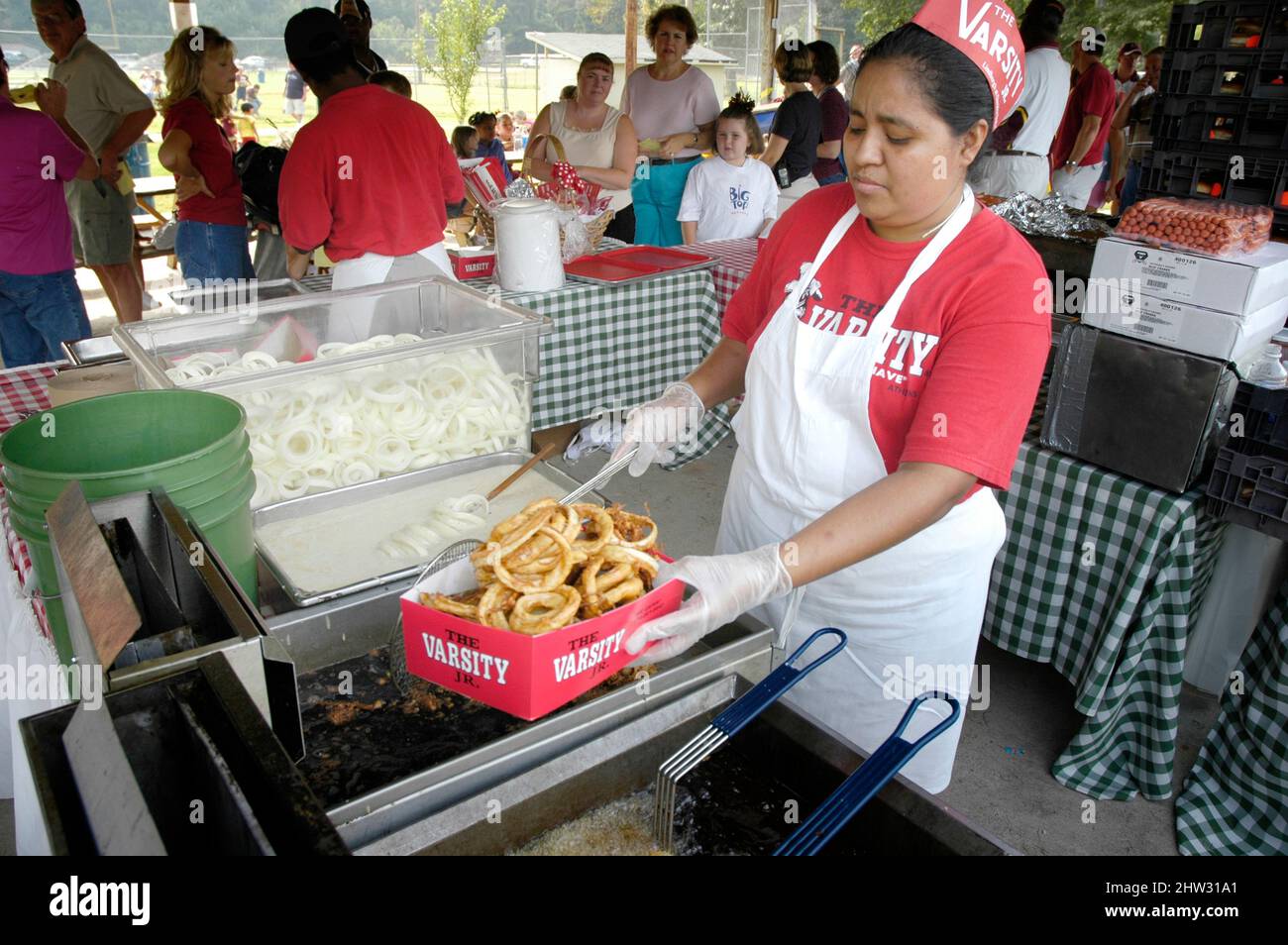 Woman making battered Onion Rings for party in deep fryer cooker in oil