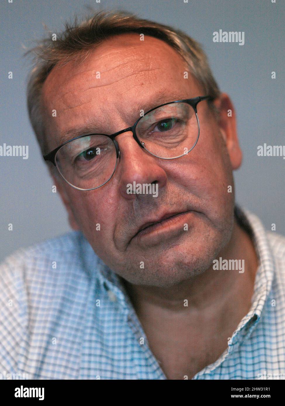 head and shoulder studio portrait of 60 year old man with reading