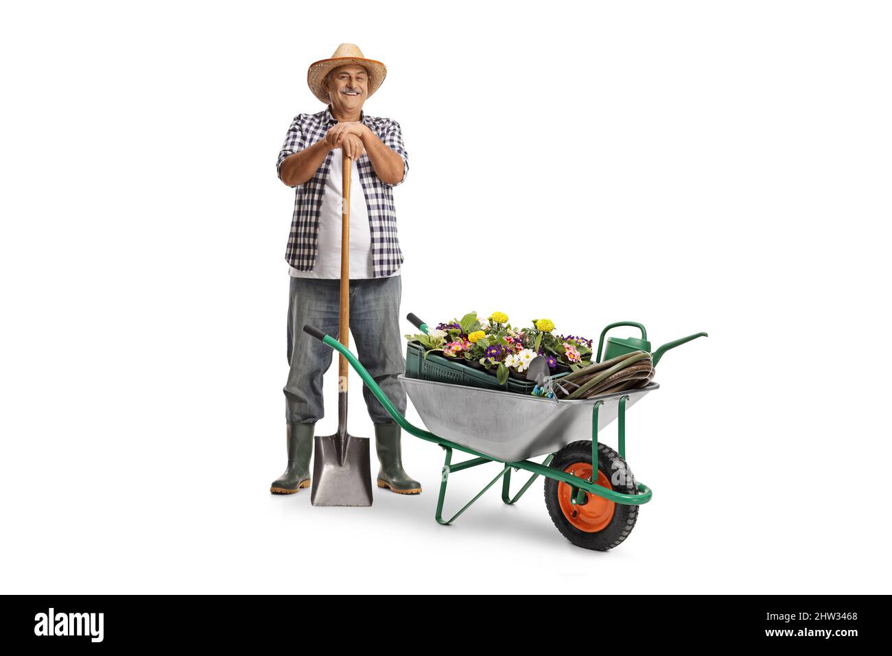 Full length portrait of a mature farmer with a shovel and a hand cart ...