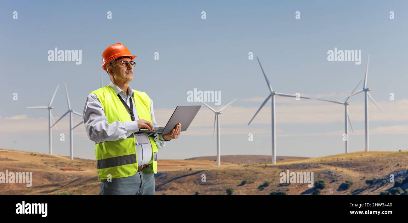 Engineer working with a laptop computer on a wind turbine farm Stock Photo