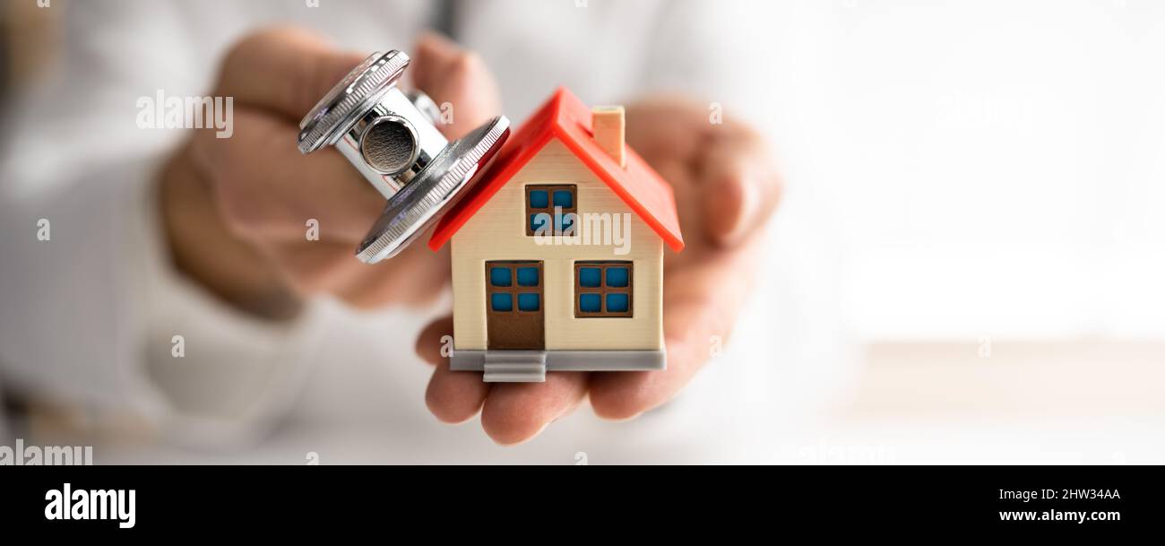 Close-up Of A Doctor's Hand Examining House Model With Stethoscope Stock Photo