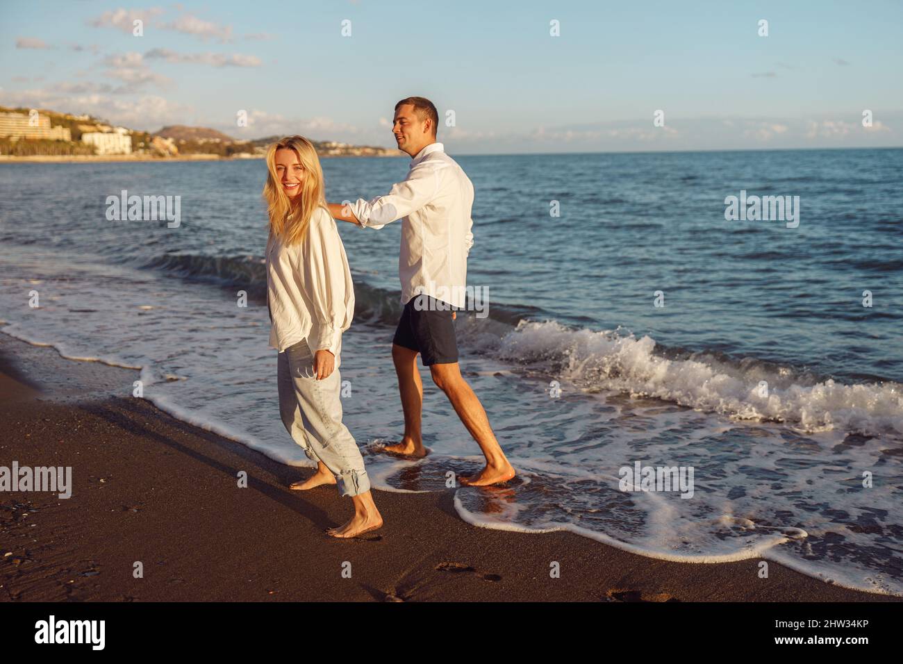 Full-length photo of happy couple walking along the beach Stock Photo