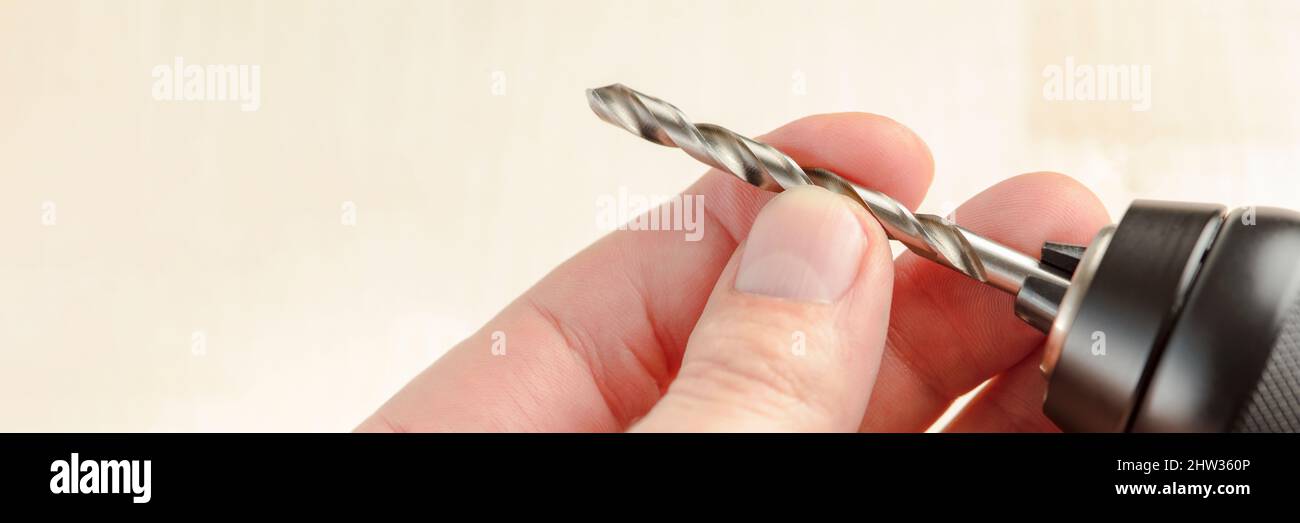 Installing a drill bit in a drill, hands take a drill and install it in