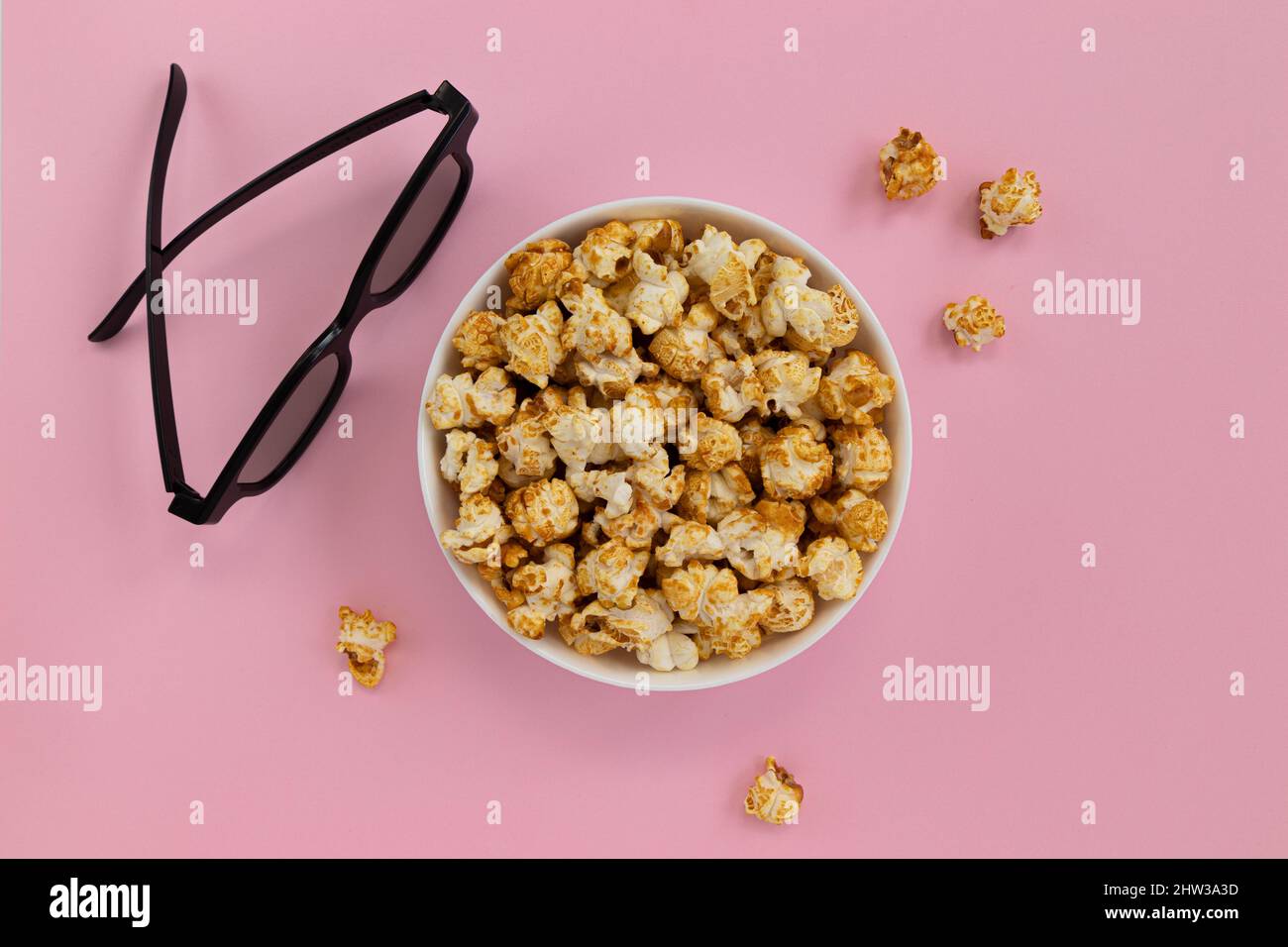 caramel popcorn in bowl and 3D glasses on pink background, home cinema, top view Stock Photo Alamy