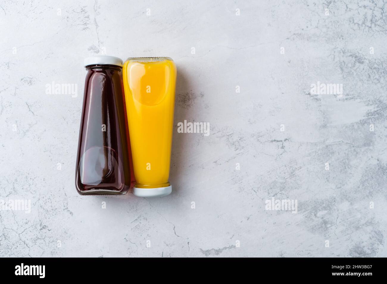 https://c8.alamy.com/comp/2HW3BG7/bottles-with-yellow-and-red-liquid-halthy-beverage-on-yellow-background-orange-and-cherry-juice-2HW3BG7.jpg