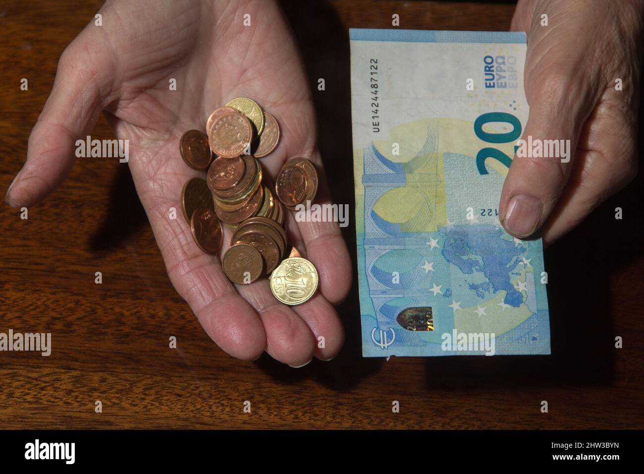Wrinkled hands of elderly woman holding coins and bankbote Stock Photo