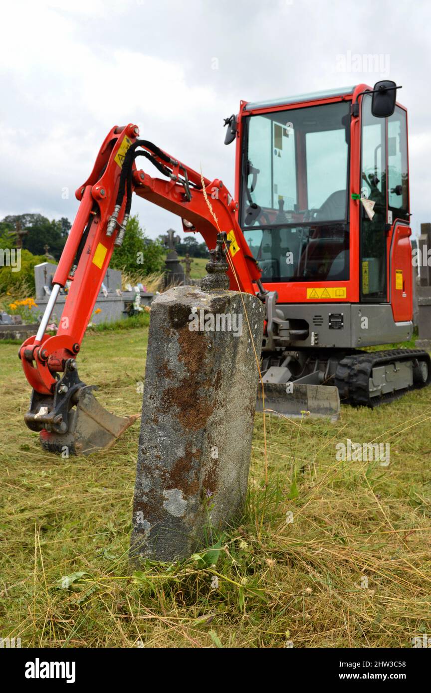 An excavator for digging a grave in a cemetery for burial or exhumation. Stock Photo