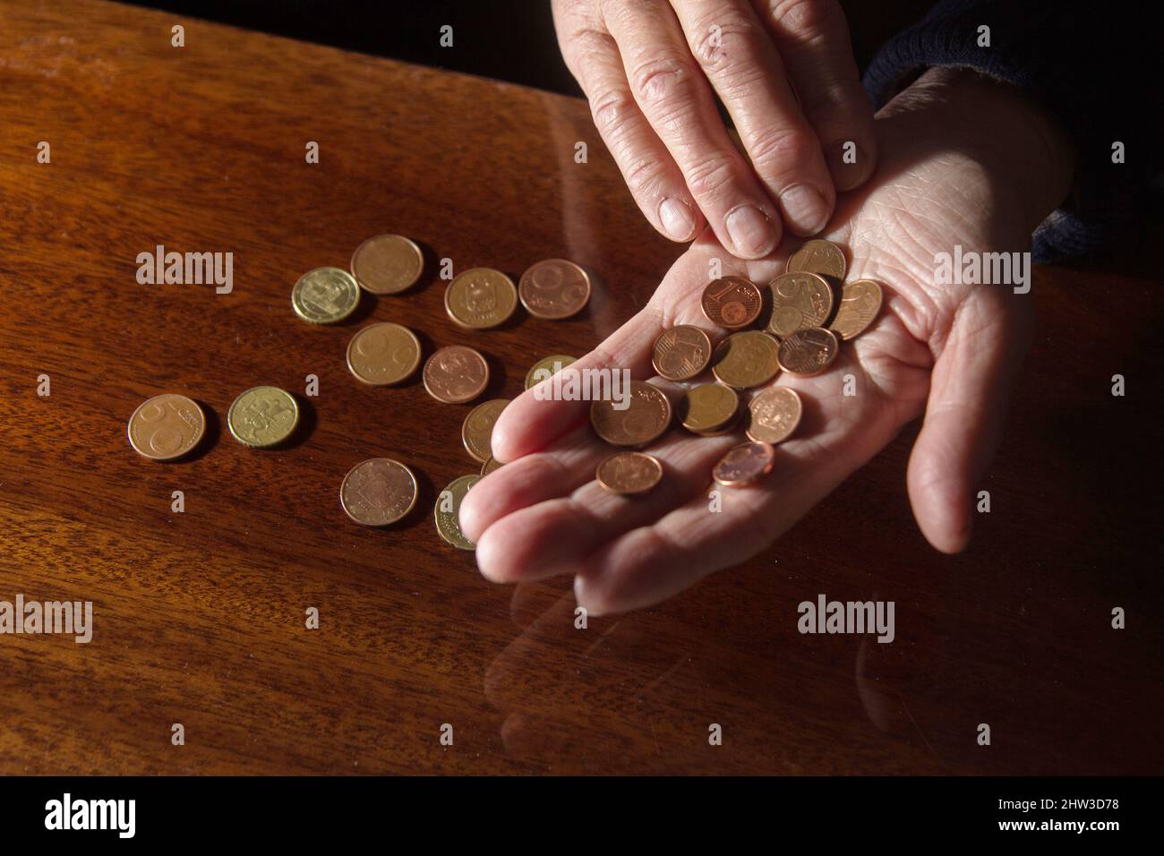 Wrinkled hands of elderly woman counting coins Stock Photo