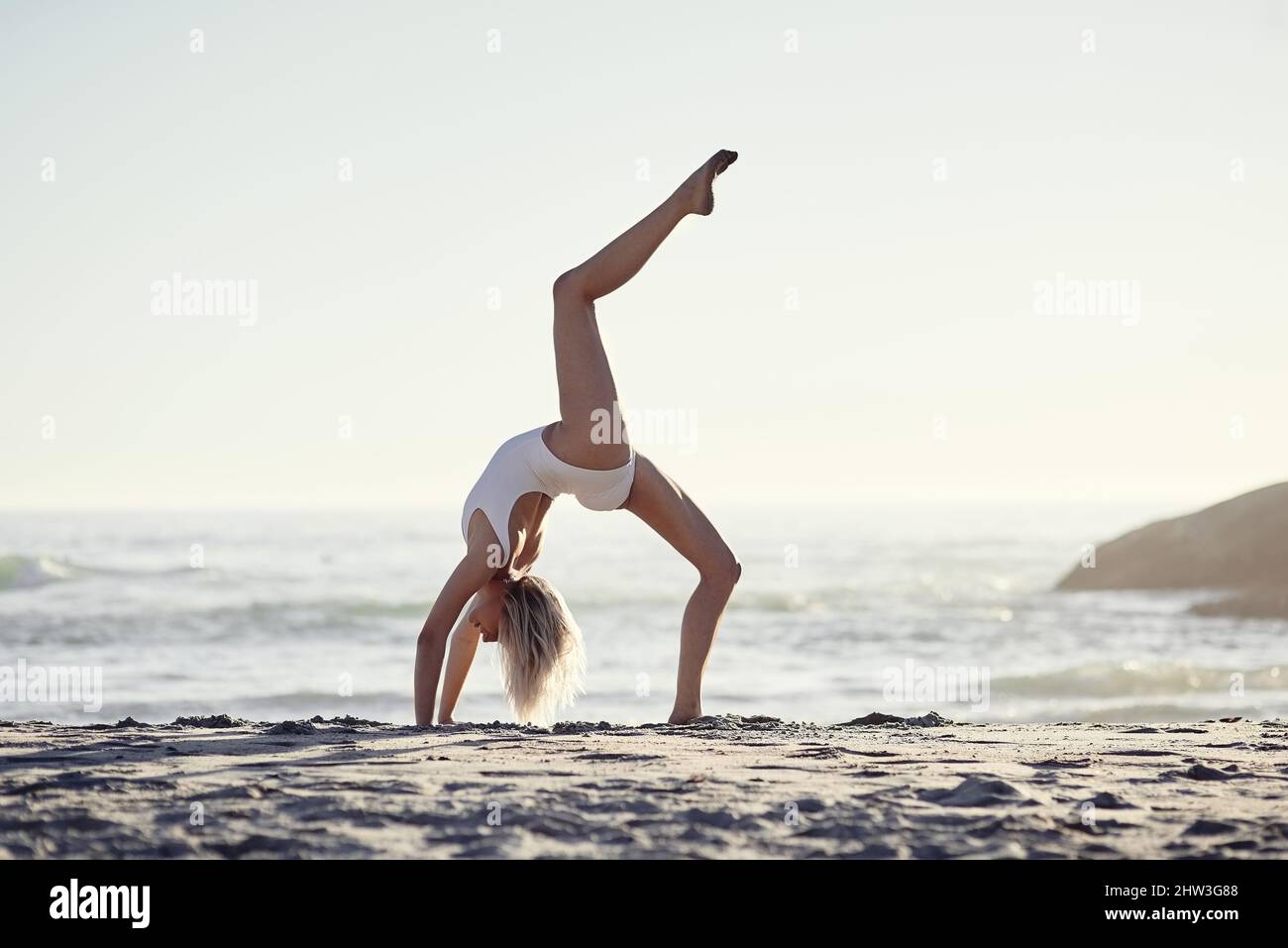 As free as the ocean. Full length shot of a young woman doing a handstand on the beach. Stock Photo