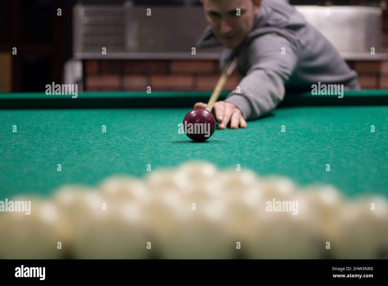 Guy plays billiards. Man hits balls. Student plays balls in bar