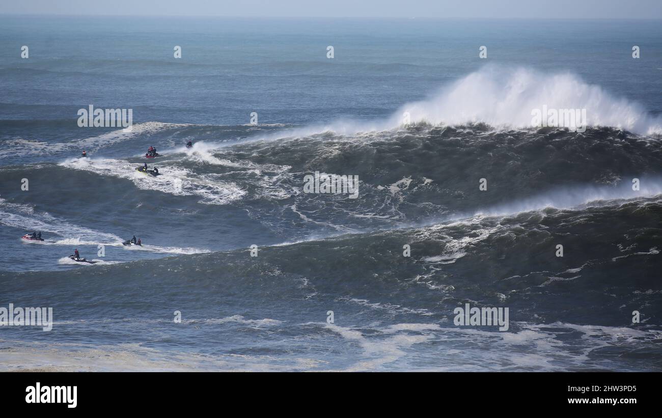 Jet skis in Praia do Norte positioning themselves on a big waves day. Nazaré, Portugal. Stock Photo