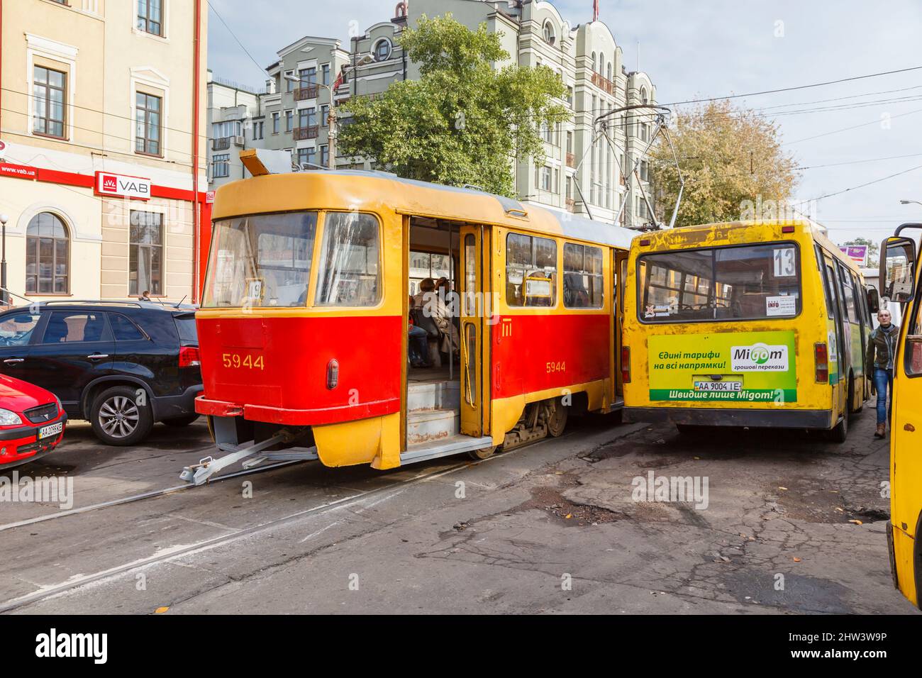 Public transport in downtown Kiev (Kyiv), capital city of Ukraine: a typical red and yellow tramcar and battered yellow bus in Kontraktova Ploshcha Stock Photo