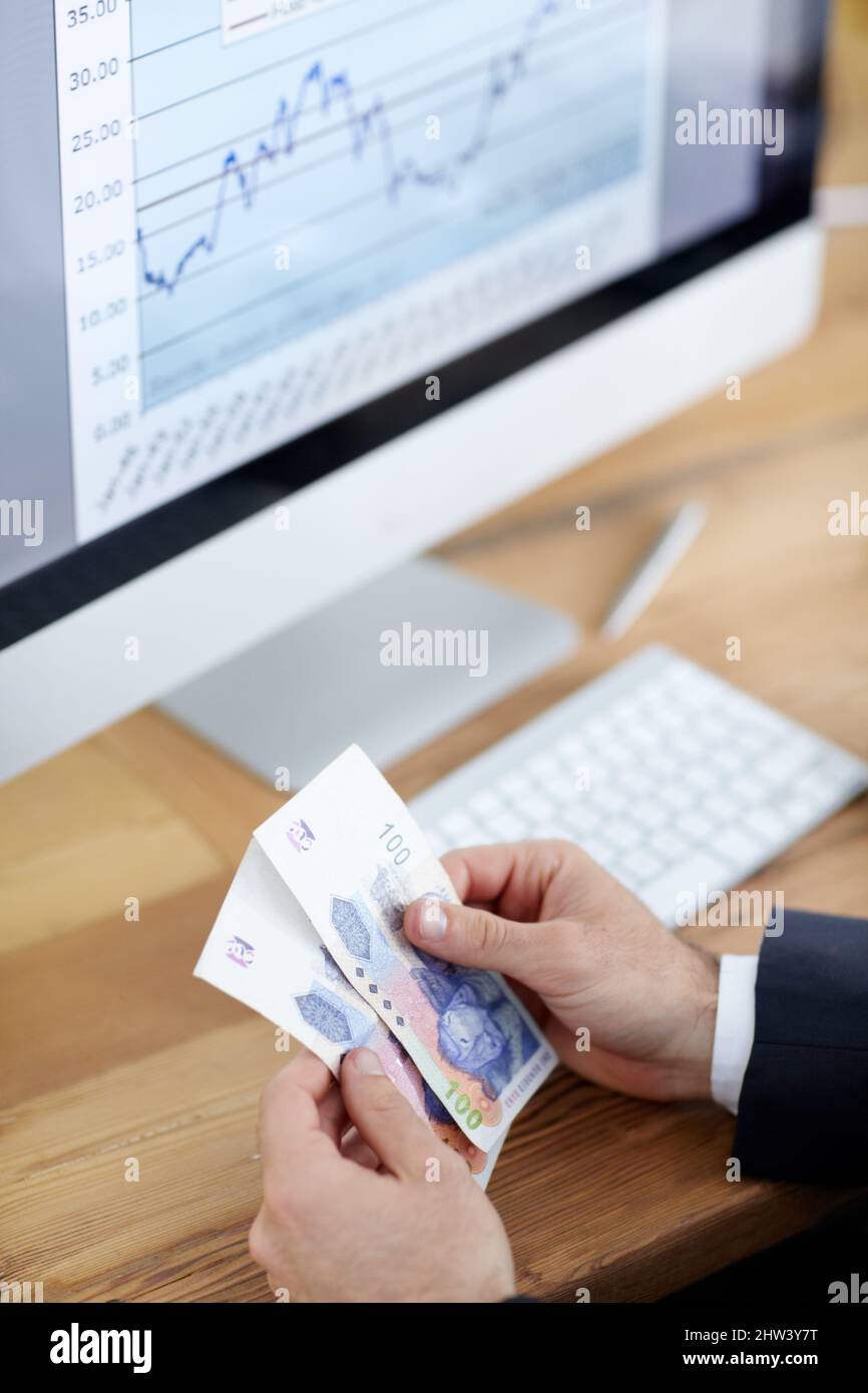 Deciding to invest his last bit of money. Cropped shot of a businessman counting money in front of a computer. Stock Photo
