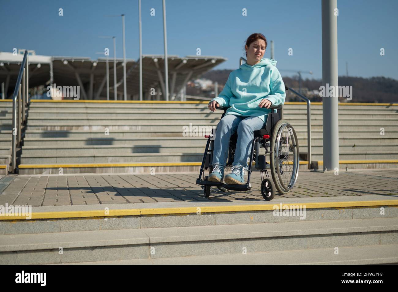A caucasian woman in a wheelchair cannot go down stairs without a ramp