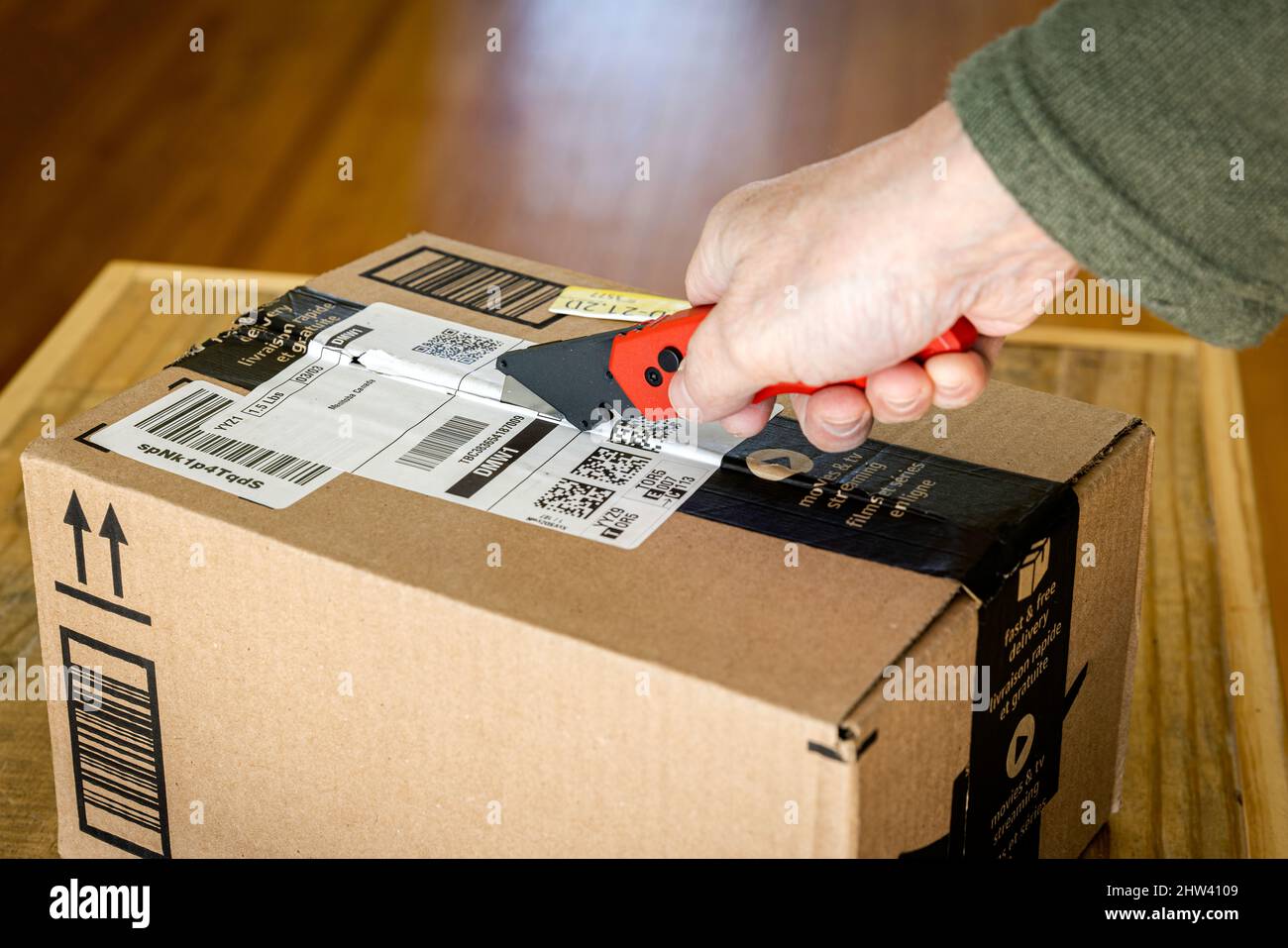 Opening a cardboard box with a utility knife. Stock Photo