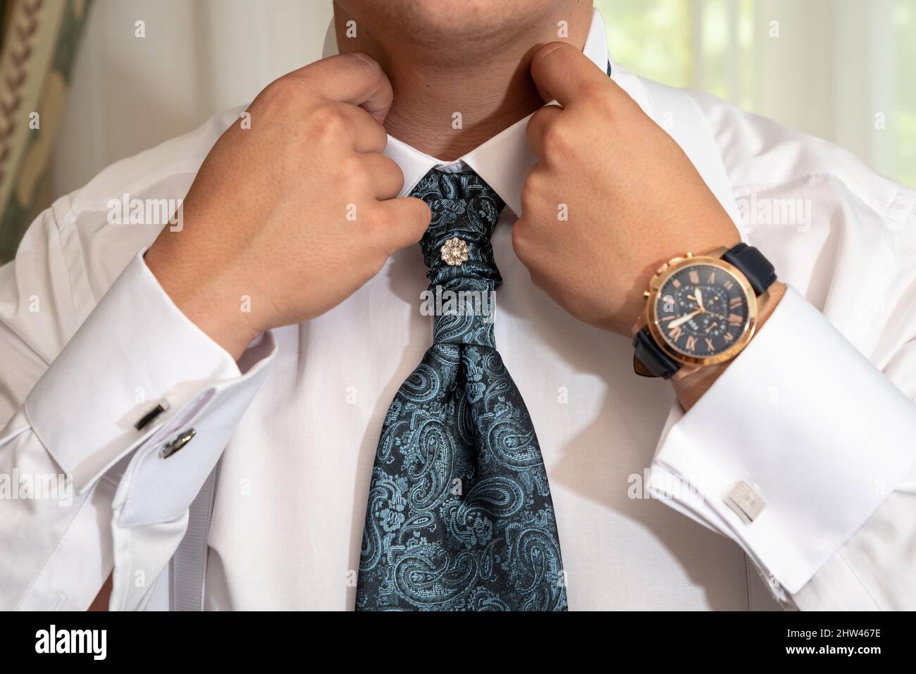 Man correcting his collar wearing a tie and a watch Stock Photo Alamy