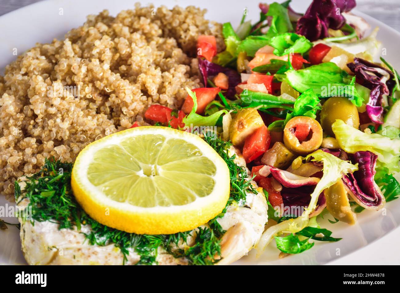 Fresh delicious vegetarian lunch. Fish with lettuce and quinoa on white ...