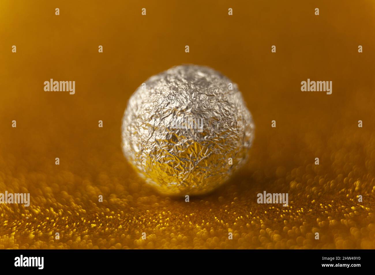 silver aluminium ball on gold background, close up, macro, copy space Stock Photo