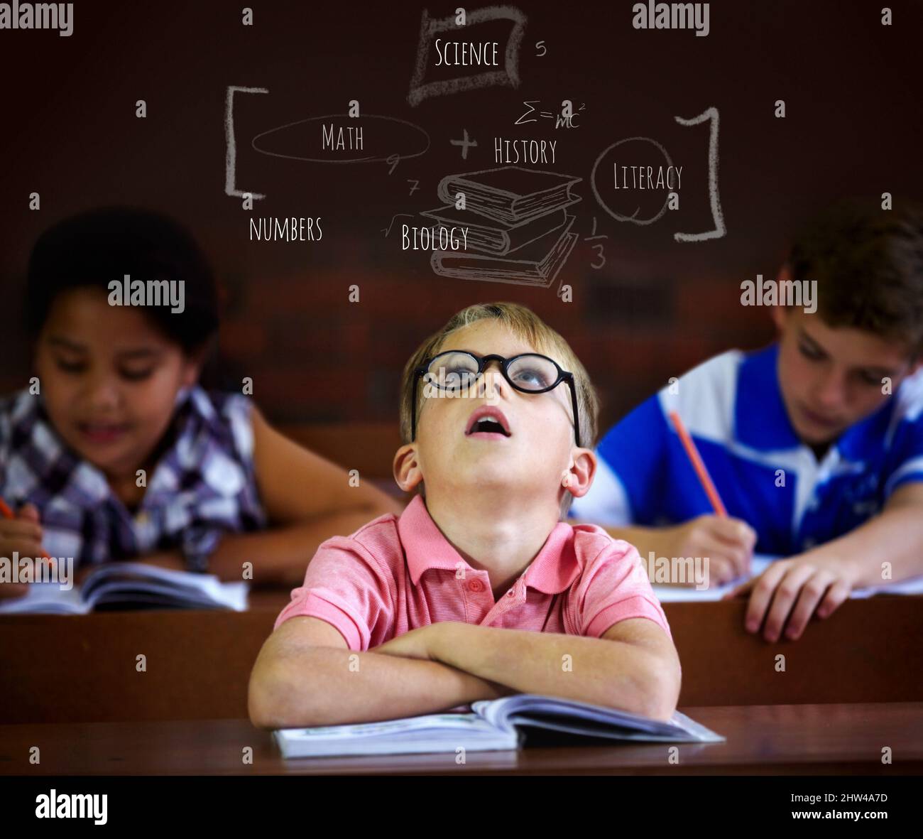 Theres so much to learn. Young boy feeling overcome with boredom in the classroom. Stock Photo