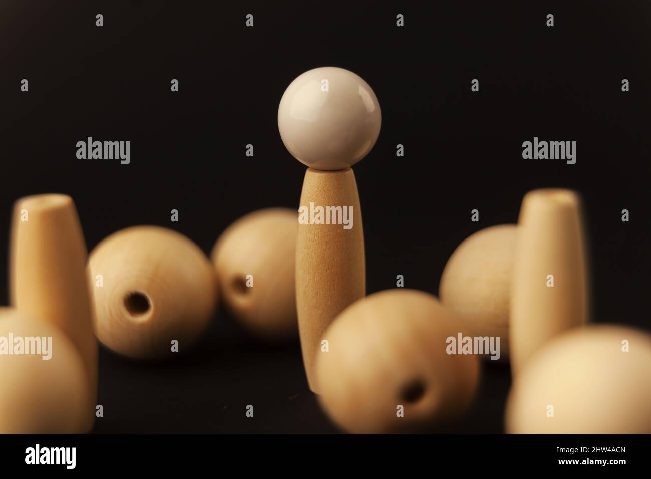 wooden balls and white ball on cylinder on black background, alone against all, close up Stock Photo
