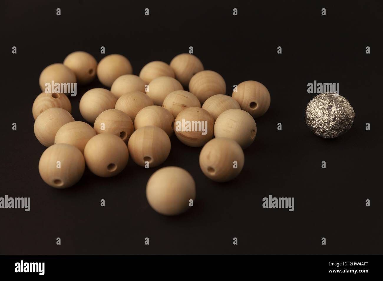 wooden balls against one silver ball, alone against all, close up Stock Photo