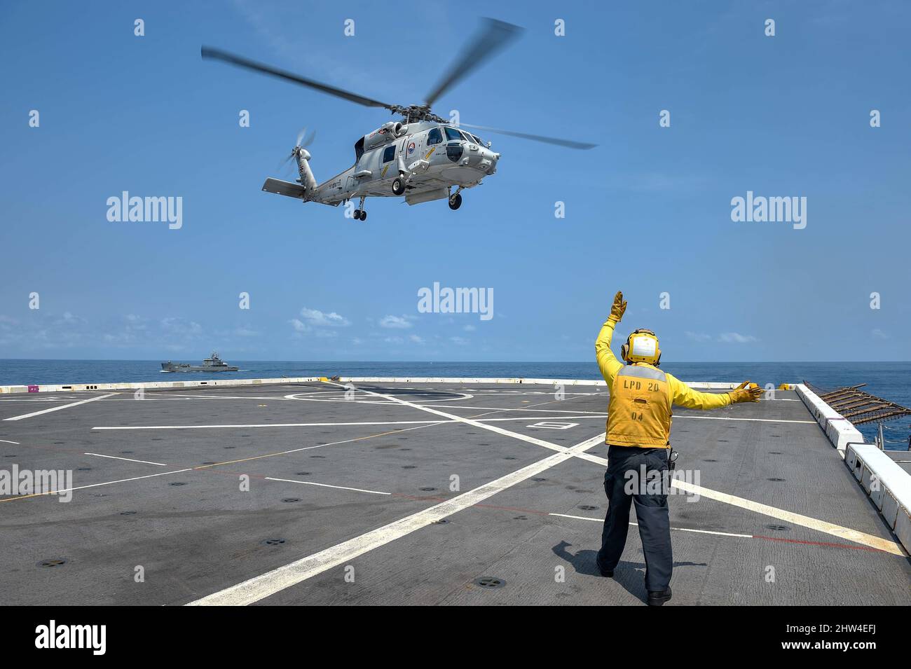 GULF OF THAILAND (March 1, 2022) Aviation Boatswain’s Mate (Handling) 2nd Class John Montano, from Oakdale, Calif., assigned to the amphibious transport dock ship USS Green Bay (LPD 20), signals an SH-70B Sea Hawk helicopter from the Royal Thai Navy to take off from the flight deck during exercise Cobra Gold 22. Cobra Gold 2022 is the 14st iteration of the international training exercise that supports readiness and emphasizes coordination on civic action, humanitarian assistance, and disaster relief. From Feb. 22 through March 4, 2022, this annual event taking place at various locations throug Stock Photo