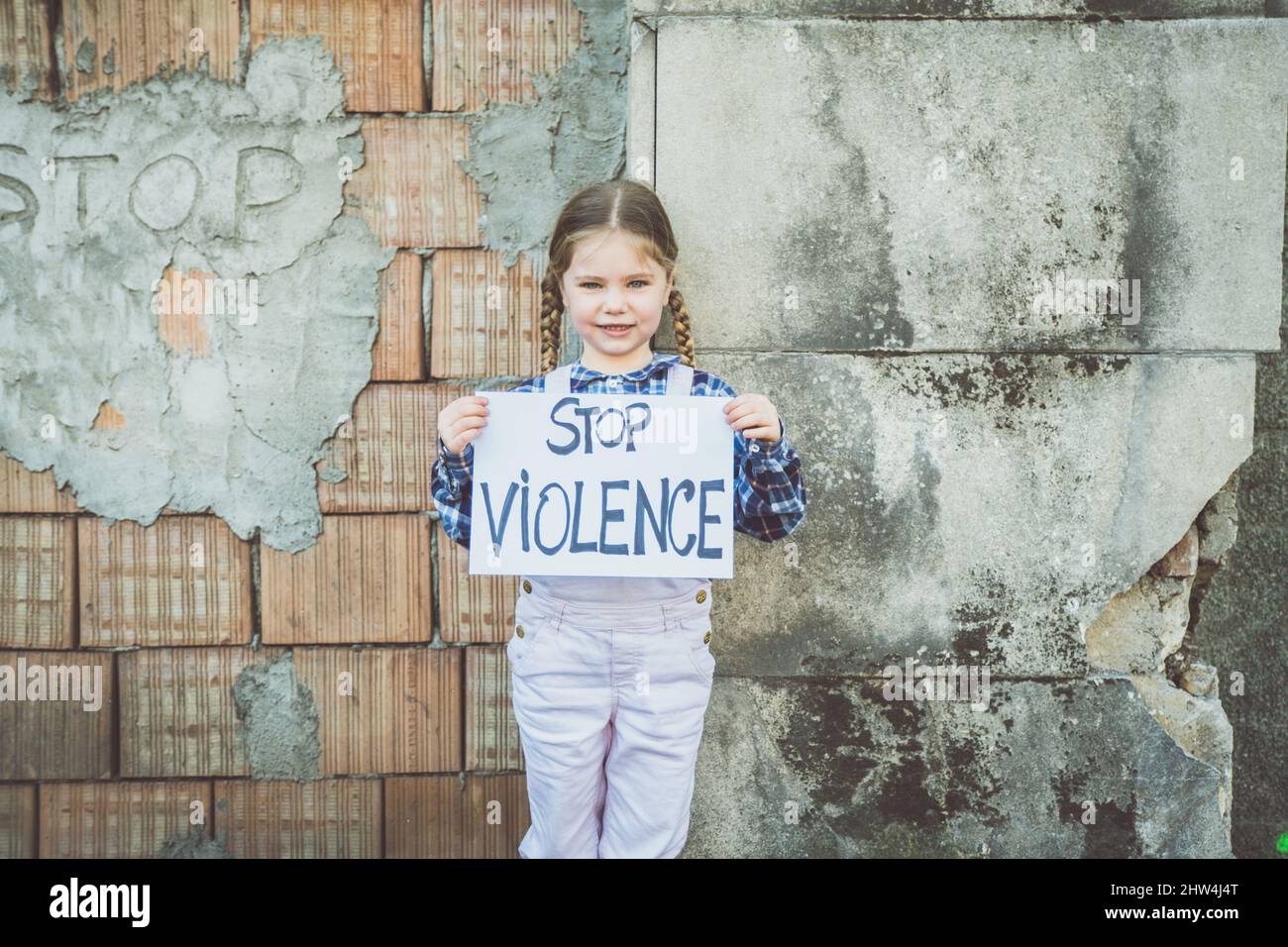 Child girl holding a poster with written STOP VIOLENCE in support of peace. Concept of 'no war' in Ukraine and in the world. Russian conflict in suppo Stock Photo