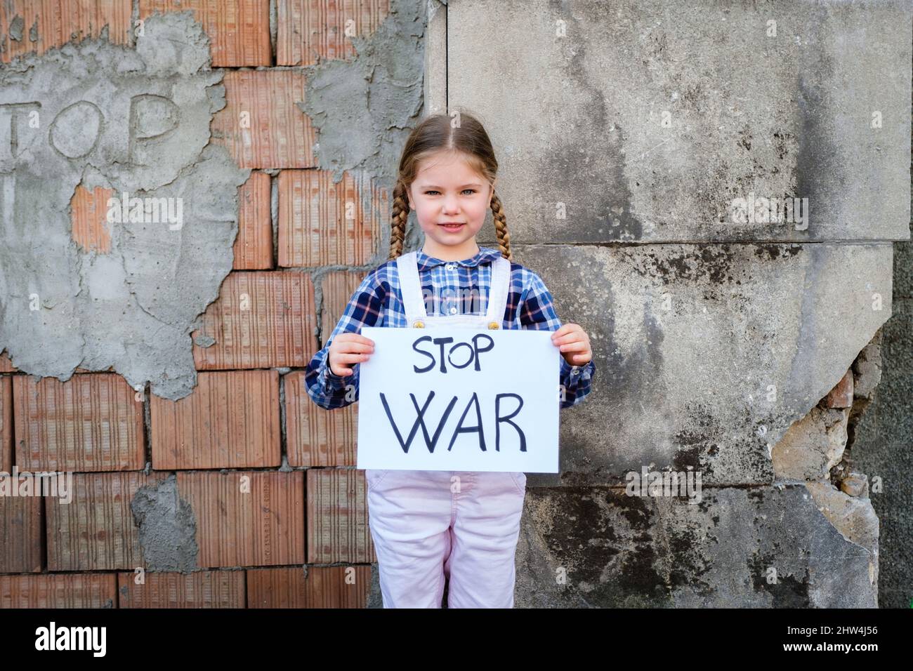 Child girl holding a poster with written STOP WAR in support of peace. Concept of 'no war' in Ukraine and in the world. Russian conflict in support of Stock Photo