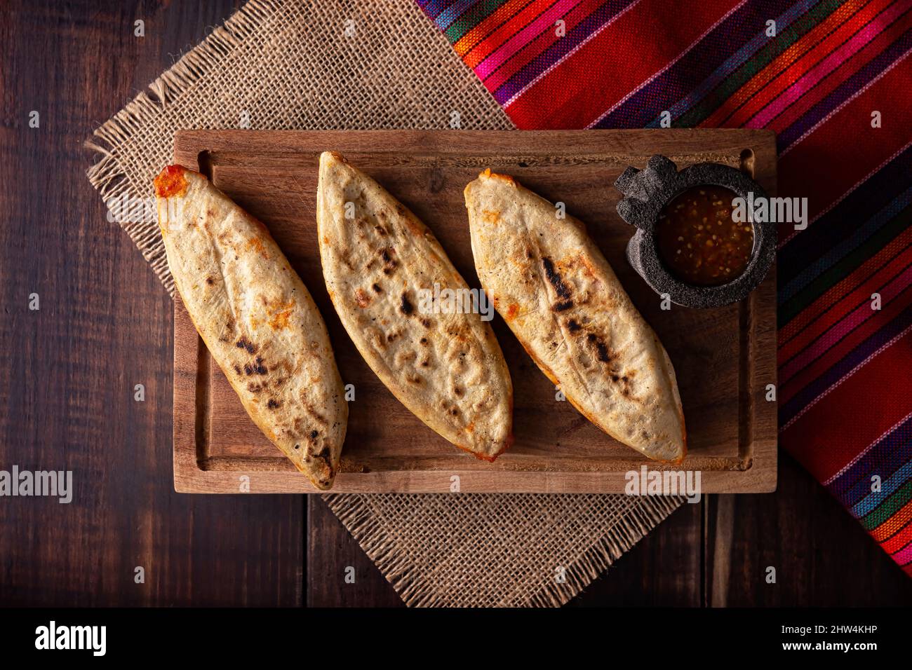 Tlacoyos. Mexican pre hispanic dish made of corn flour patty filled with chicharron prensado (pressed pork rinds). Popular street food in Mexico. Stock Photo