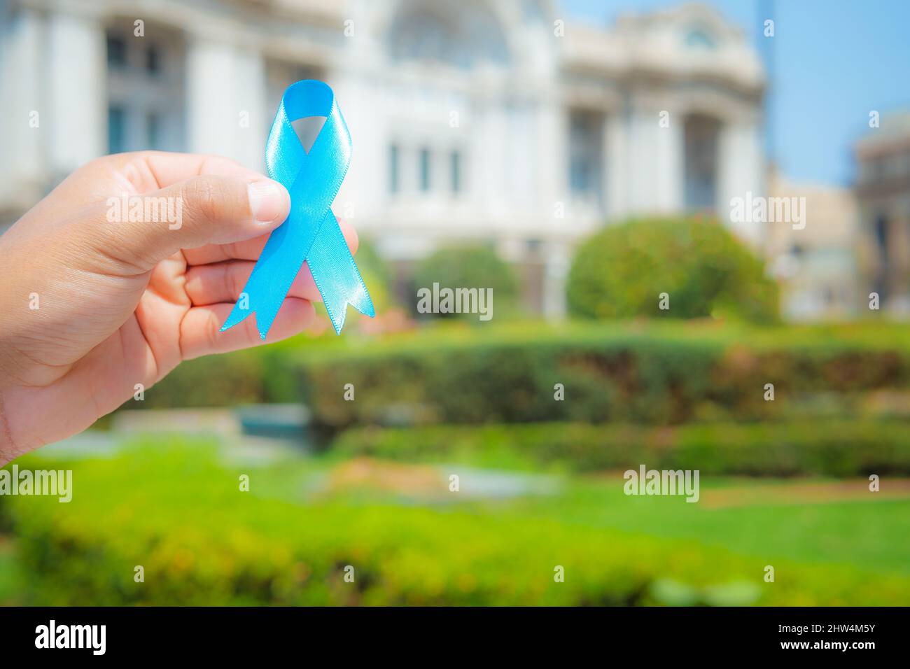November Prostate Cancer Awareness month, woman holds up a blue ribbon with her hand to support those living with and sick. World Cancer Day concept Stock Photo