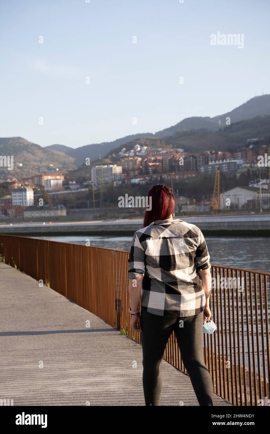 A young woman with long hair walking down the street with her hair ...