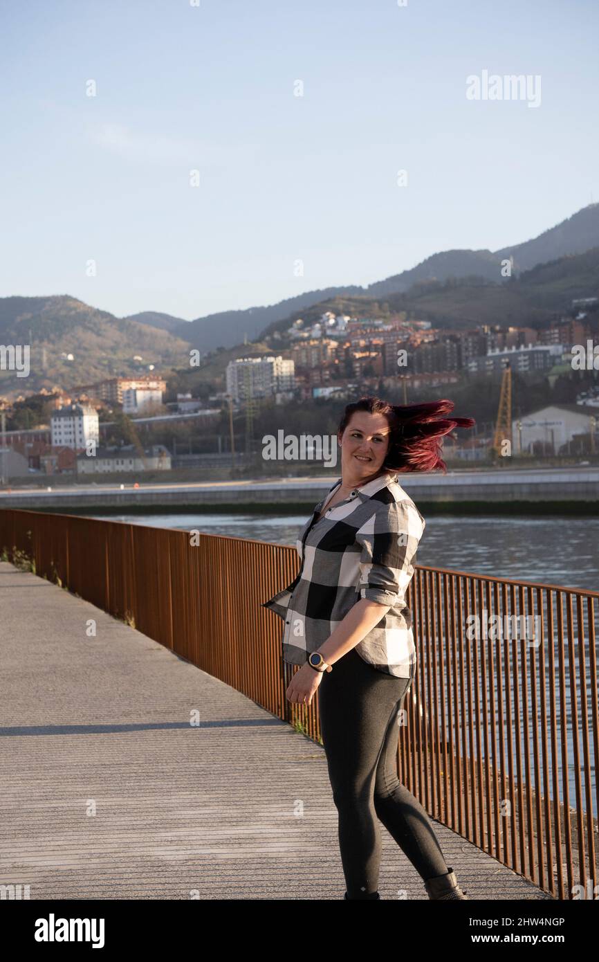 A young woman with long hair walking down the street with her hair ...