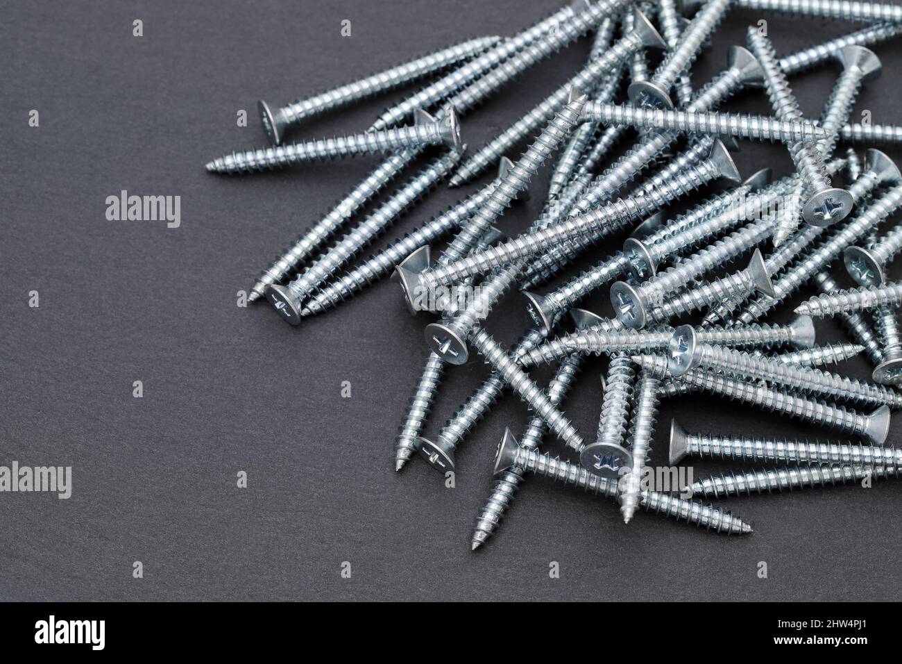 Pile of silver metallic tapping screws on black background Stock Photo
